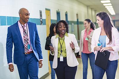 Multiracial group of teachers walking in school hallway