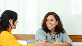 Two women in discussion, casual meeting, smiling