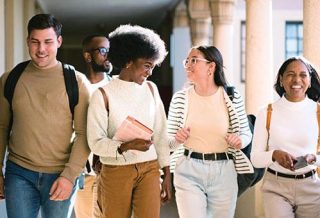 group of students talking and laughing while walking down a school hallway