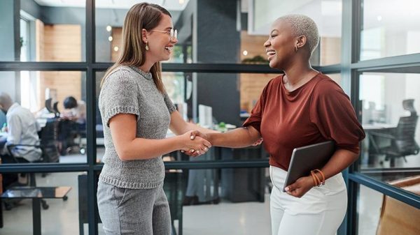 two women shaking hands in a professional environment