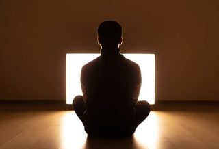The male sitting on the floor in front of the television in the dark room